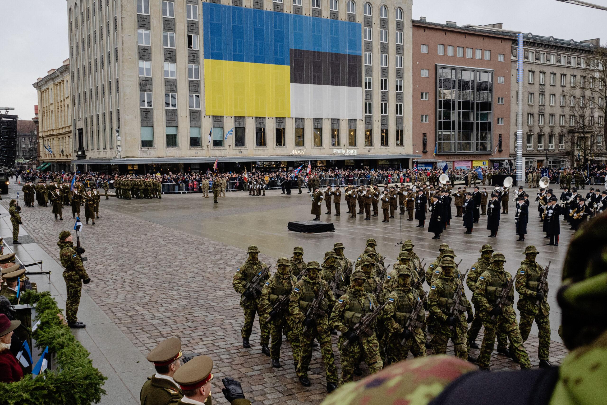 A military parade in Estonia is seen with the Ukranian flag and Estonia flag draped on a large building.
